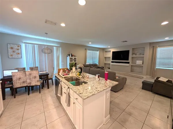 a open kitchen with stainless steel appliances kitchen island granite countertop a table and chairs in it