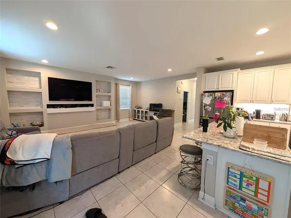 a living room with furniture a flat screen tv and kitchen view