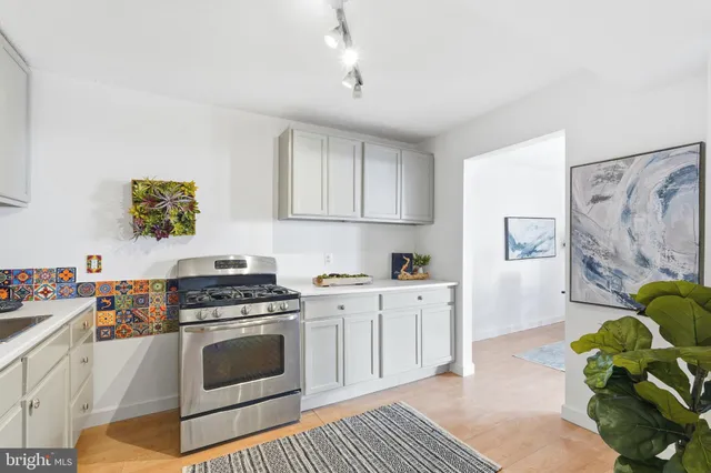 a kitchen with stainless steel appliances a stove a sink a refrigerator cabinets and a window