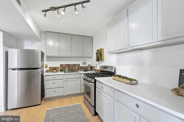 a kitchen with a refrigerator a stove and white cabinets