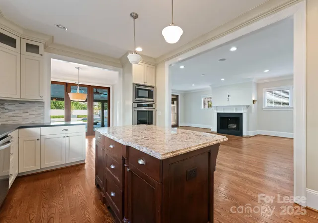 a kitchen with a stove a sink a kitchen island with chairs and wooden floor