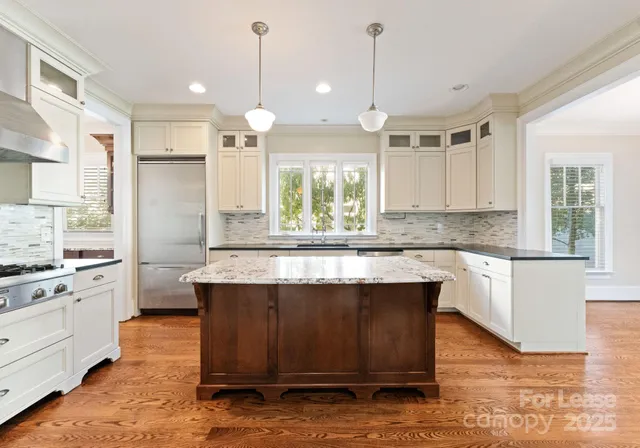 a kitchen with kitchen island granite countertop a stove a sink a center island and wooden floor