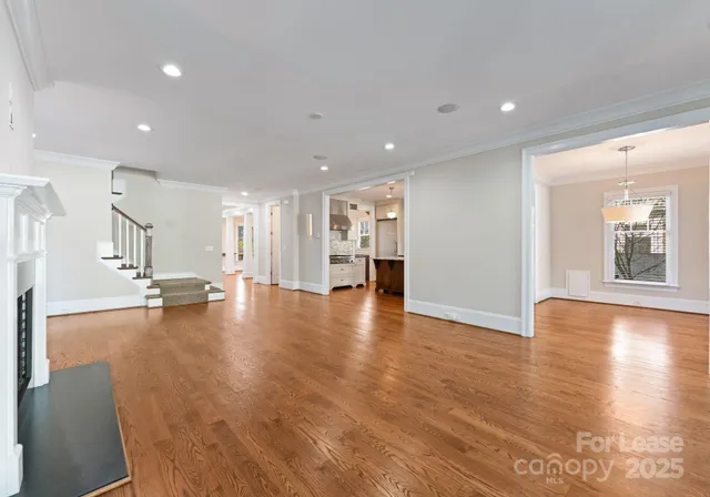 a view of empty room with wooden floor and kitchen