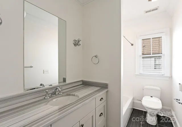 a bathroom with a granite countertop sink toilet and mirror