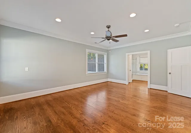 a view of an empty room with window and wooden floor