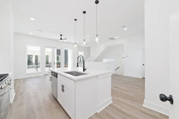 a kitchen with a sink a stove and a wooden floor