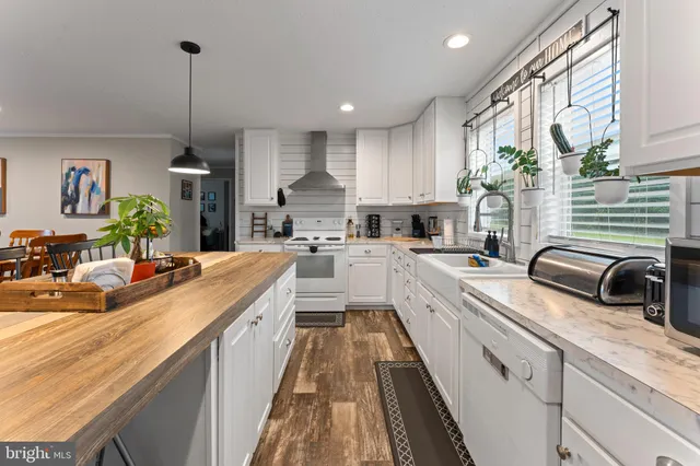 a kitchen with stainless steel appliances kitchen island granite countertop a table chairs sink and cabinets