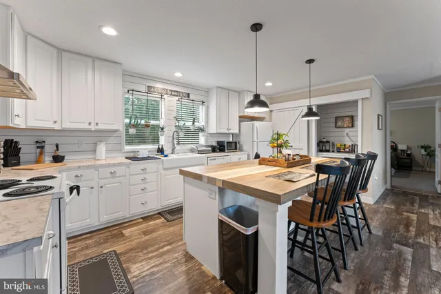 a kitchen with stainless steel appliances granite countertop a dining table chairs refrigerator and microwave