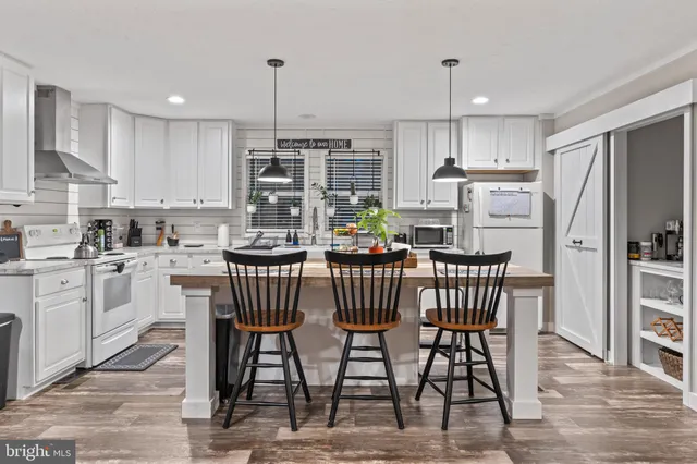 a kitchen with stainless steel appliances kitchen island granite countertop a table chairs sink and cabinets