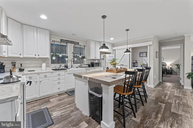 a kitchen with stainless steel appliances kitchen island granite countertop a dining table chairs and a refrigerator