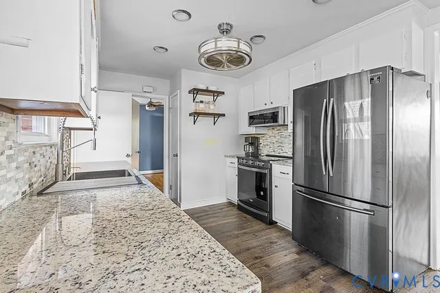 a kitchen with granite countertop a refrigerator and a stove top oven