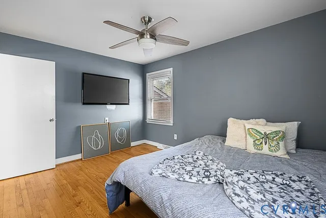 a bedroom with a bed a flat tv screen and a dresser