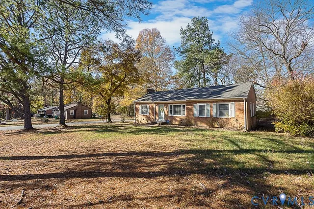 a view of a big house with a yard and large trees