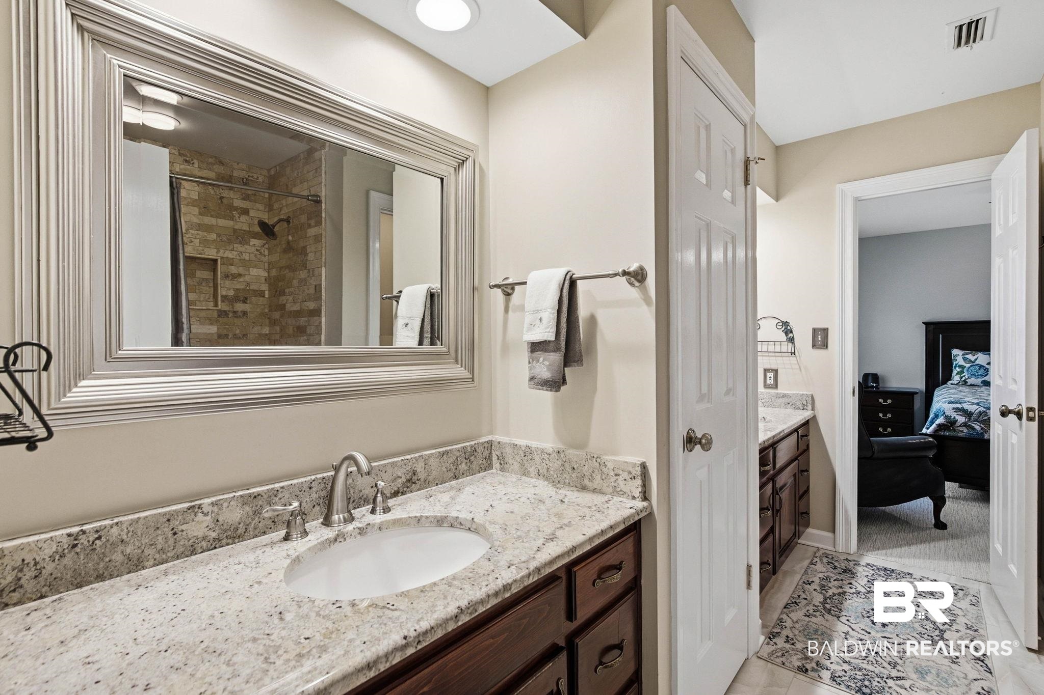 31515 Rhett Drive Spanish Fort, AL 36527 - Photo 50 of 100 The Jack and Jill bathroom has a large linen closet, private water closet, and a custom tiled shower tub combination, and granite countertops. Each side has it's own sink and vanity.