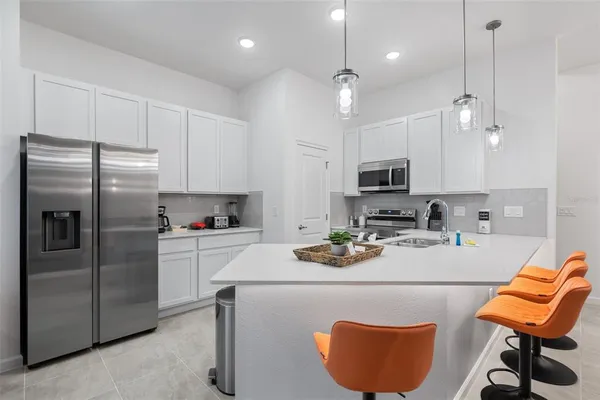 a kitchen with stainless steel appliances granite countertop a sink a stove a refrigerator cabinets and chairs