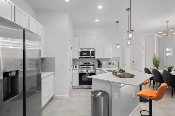 a kitchen with stainless steel appliances kitchen island granite countertop a refrigerator a stove a sink a dining table and chairs with wooden floor