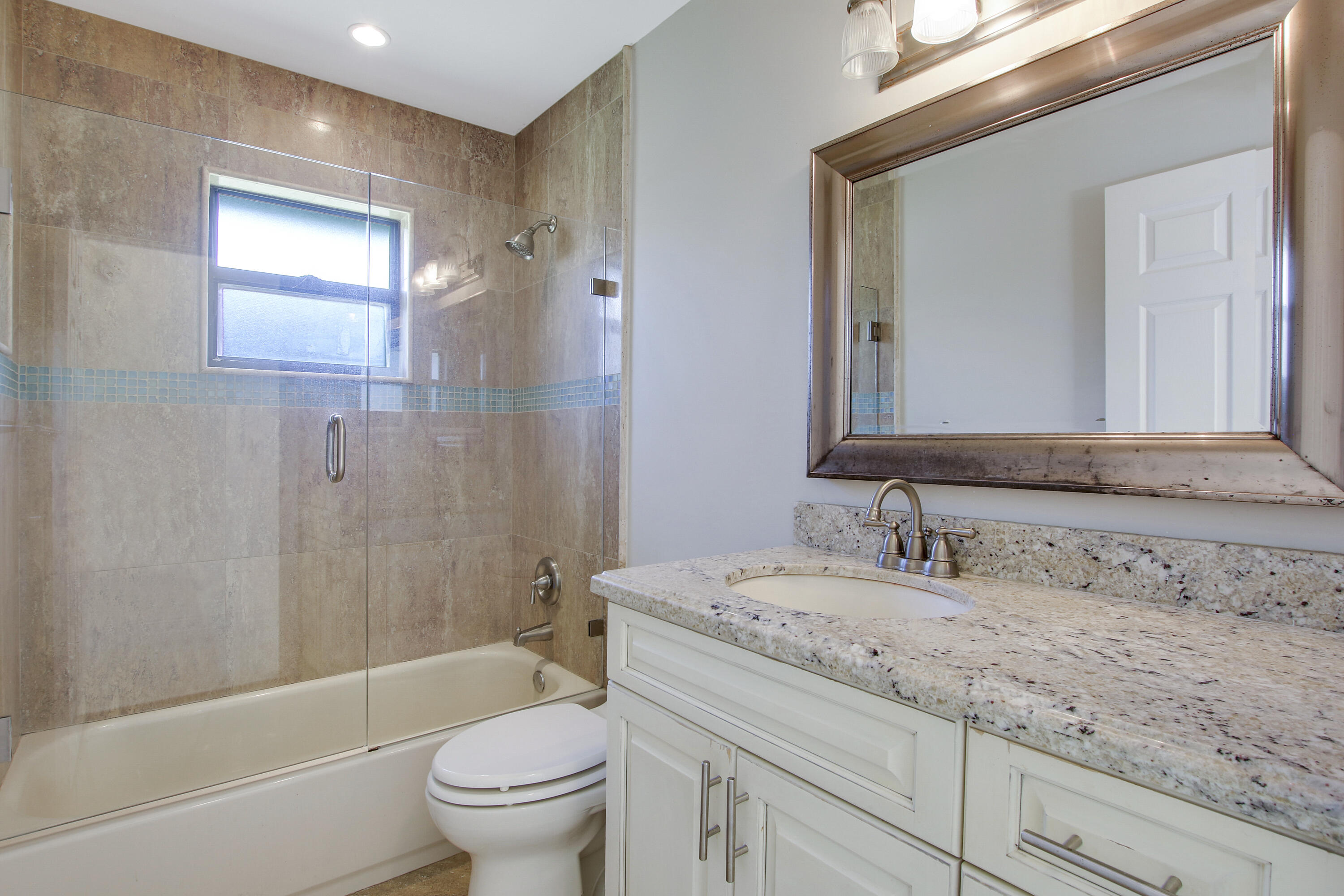 13431 153rd Road North Jupiter, FL 33478 - Photo 19 of 44 a bathroom with a granite countertop sink a toilet and a bathtub