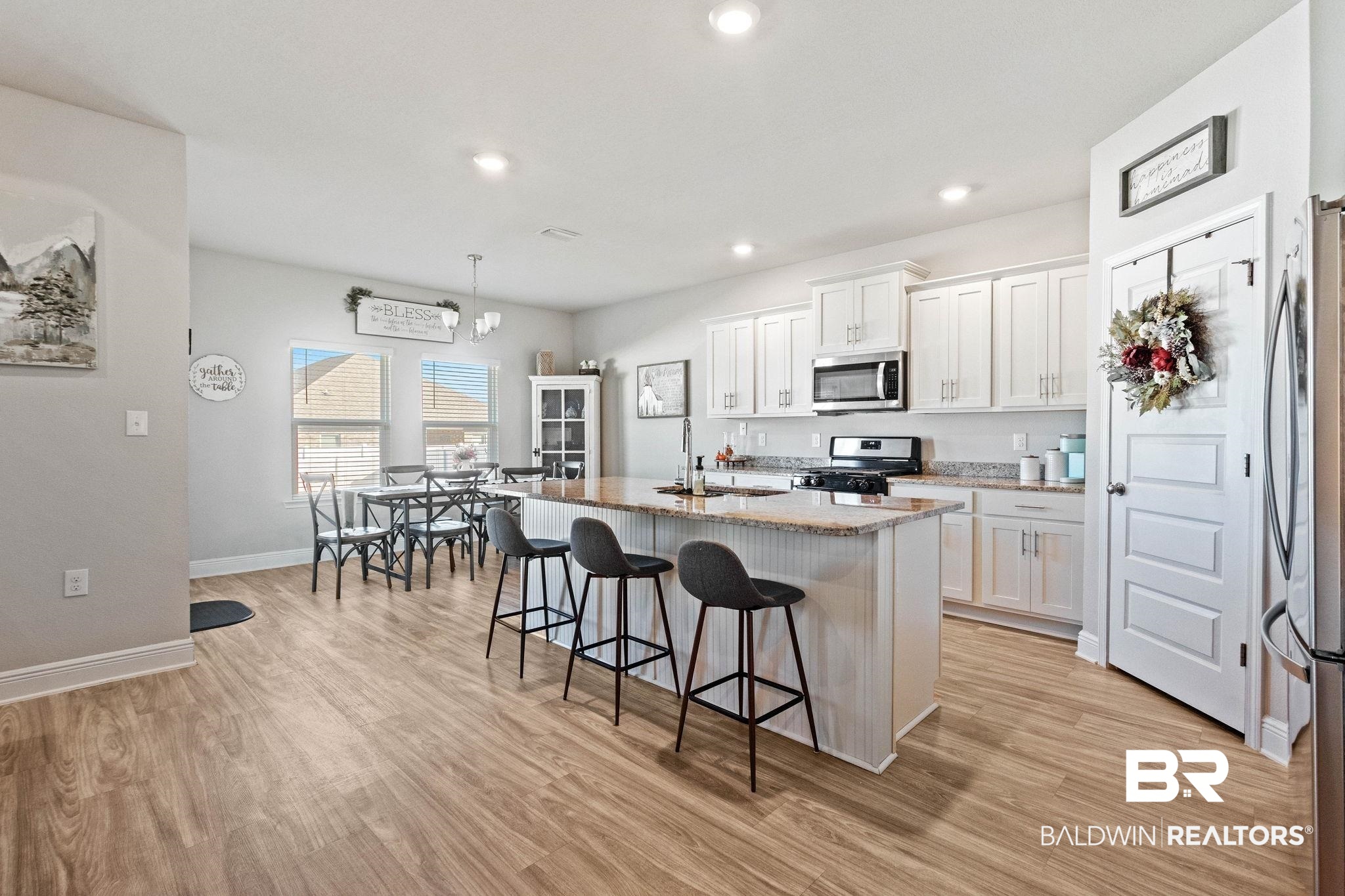 24939 Spectacular Bid Loop Daphne, AL 36526 - Photo 10 of 38 Kitchen featuring a center island with sink, light stone counters, a kitchen bar, white cabinets, and recessed lighting