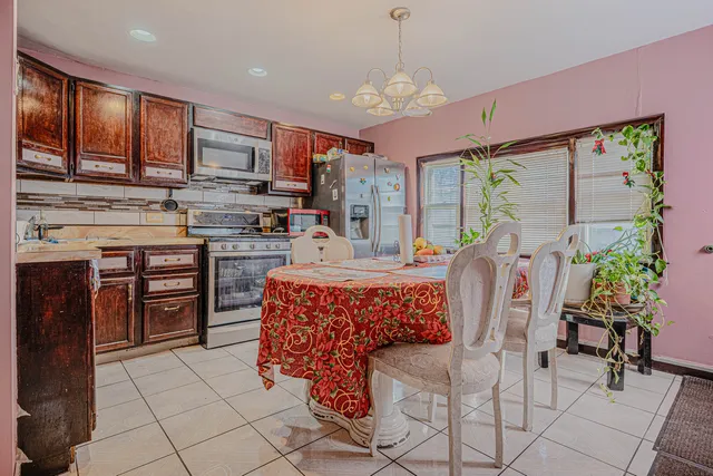 a kitchen with stainless steel appliances granite countertop a stove top oven a sink dishwasher a dining table and chairs with wooden floor