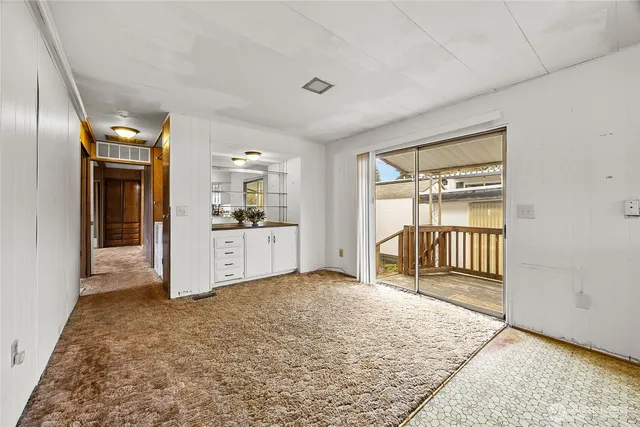 a view of a livingroom with wooden floor and kitchen space