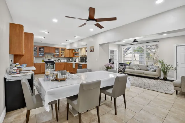 a dining room with furniture and a chandelier fan