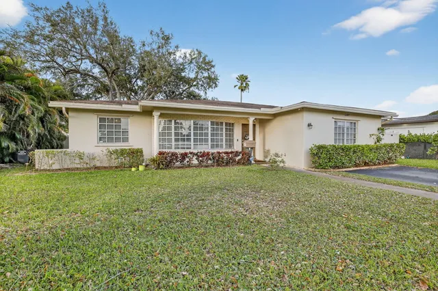 front view of house with a yard and potted plants