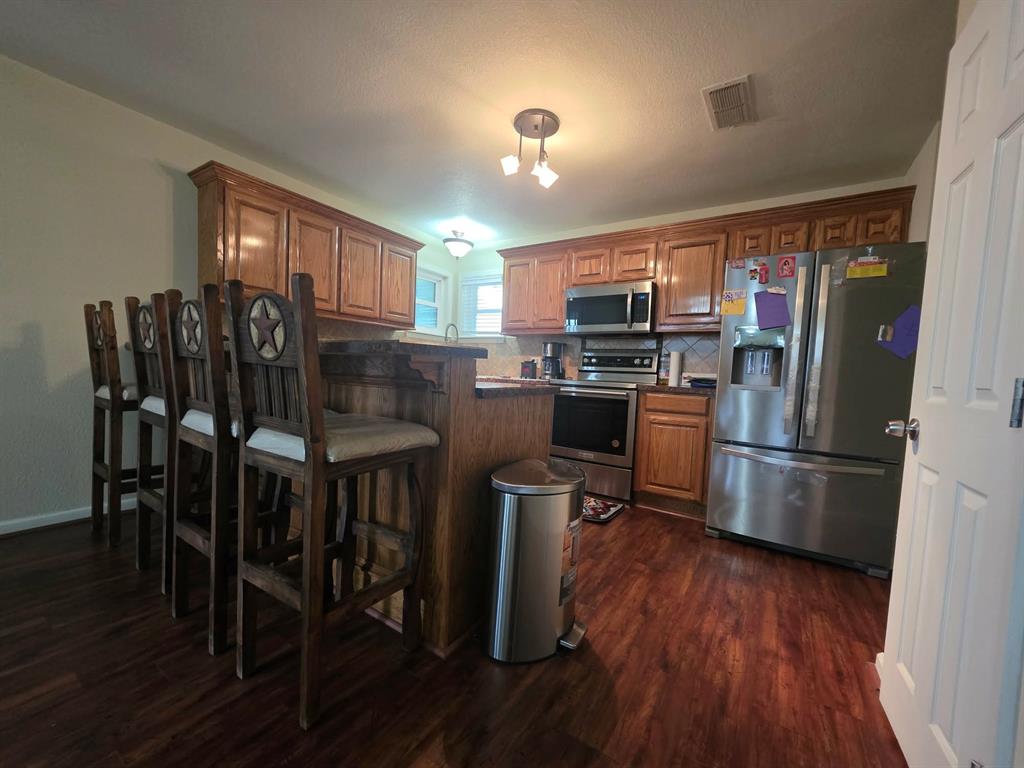 739 Bluebonnet Street Mexia, TX 76667 - Photo 11 of 28 a kitchen with kitchen island a dining table chairs and refrigerator