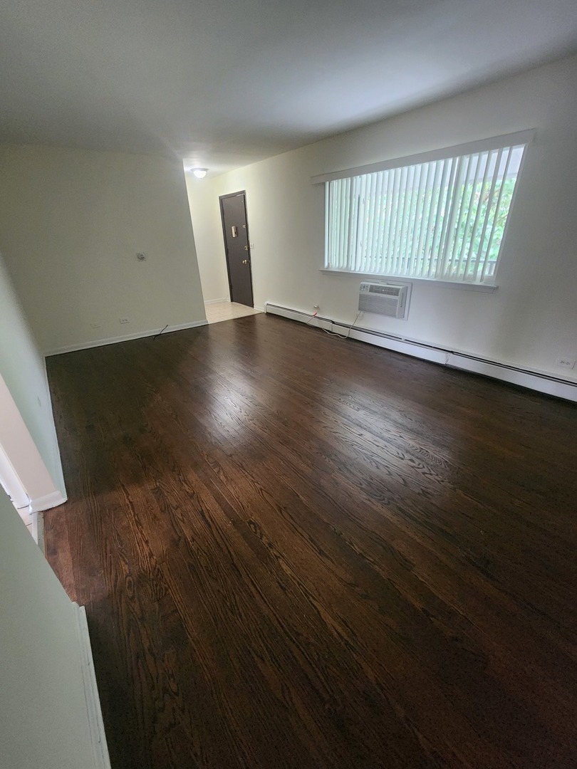 7455 North Ridge Boulevard, Unit C2 Chicago, IL 60645 - Photo 5 of 9 an empty room with wooden floor and windows