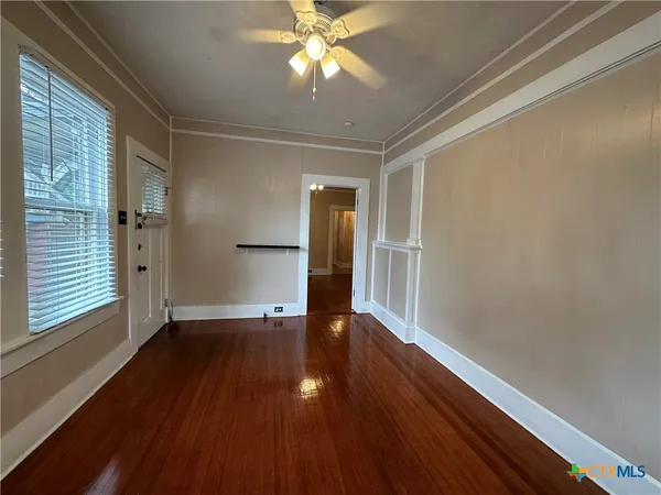 a view of an empty room with wooden floor and a window