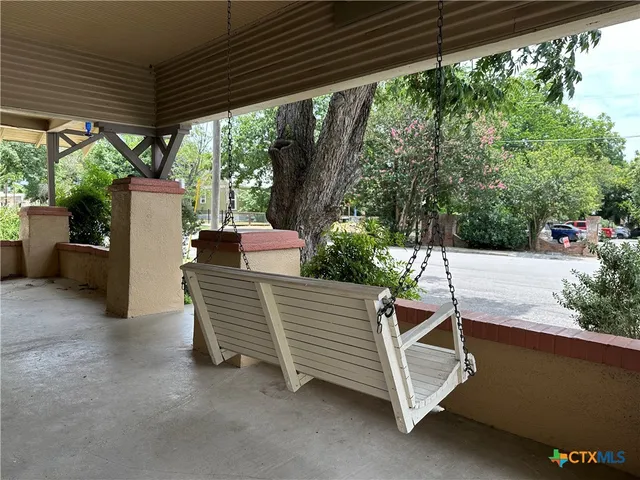 a view of a patio with table and chairs under an umbrella with a large tree