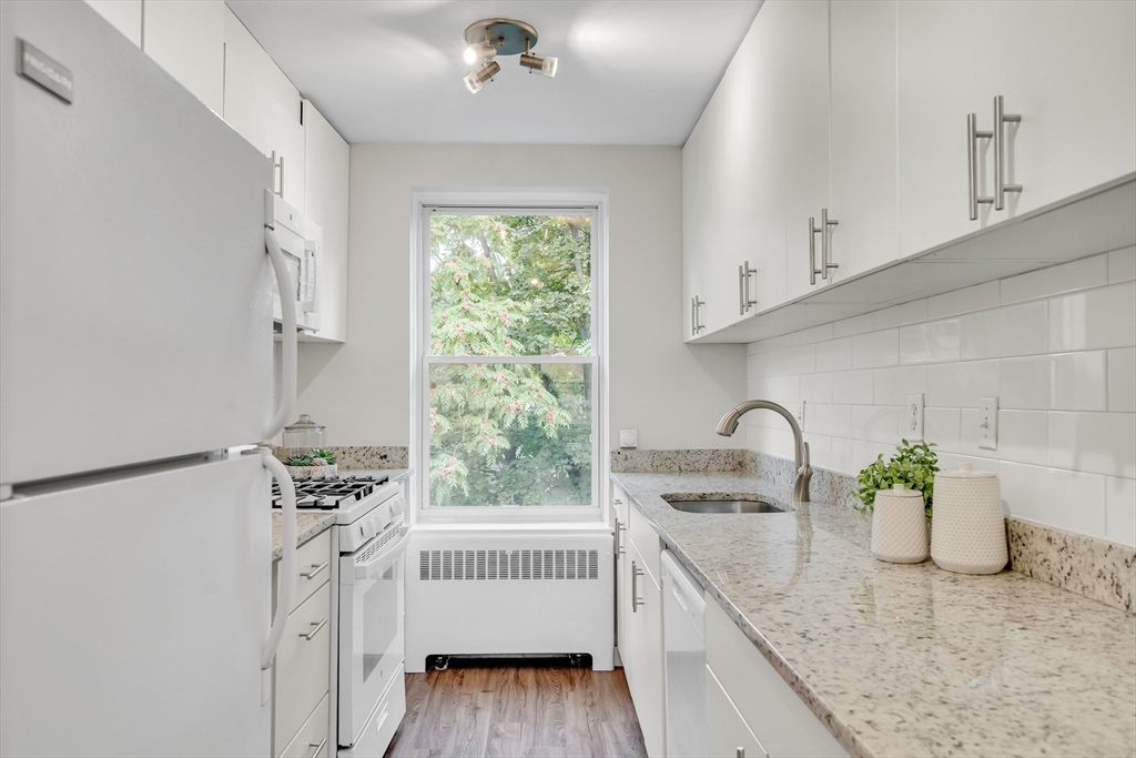 136 Beaconsfield Road, Unit 6 Brookline, MA 02445 - Photo 6 of 17 a kitchen with stainless steel appliances a sink a window and cabinets