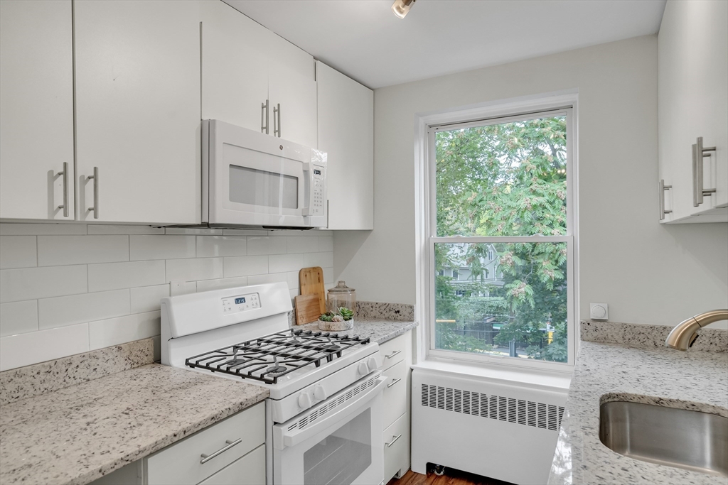 136 Beaconsfield Road, Unit 6 Brookline, MA 02445 - Photo 7 of 17 a kitchen with granite countertop a stove a sink dishwasher and cabinets with wooden floor
