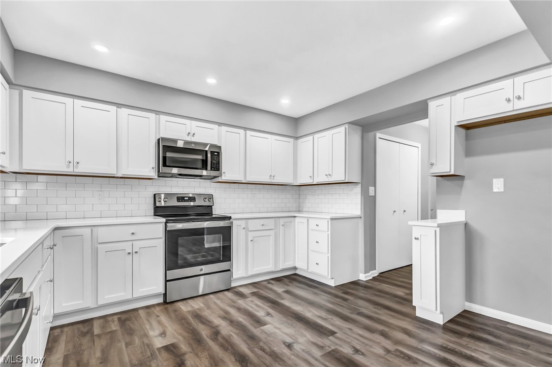 18230 Egbert Road Walton Hills, OH 44146 - Photo 6 of 34 Kitchen with dark hardwood / wood-style floors, white cabinets, tasteful backsplash, and appliances with stainless steel finishes