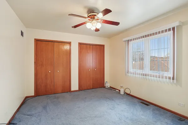 a view of an empty room with chandelier fan