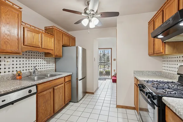 a kitchen with stainless steel appliances granite countertop a refrigerator a sink dishwasher stove and white countertops with wooden floor