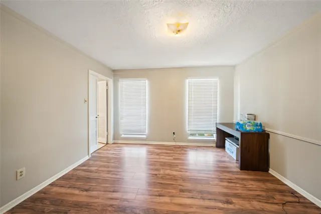 a view of an empty room with window and wooden floor