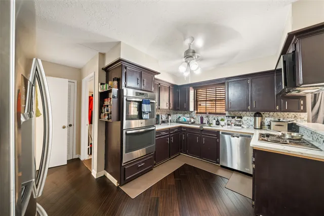 a kitchen with stainless steel appliances granite countertop a refrigerator a stove a sink and dishwasher with wooden floor