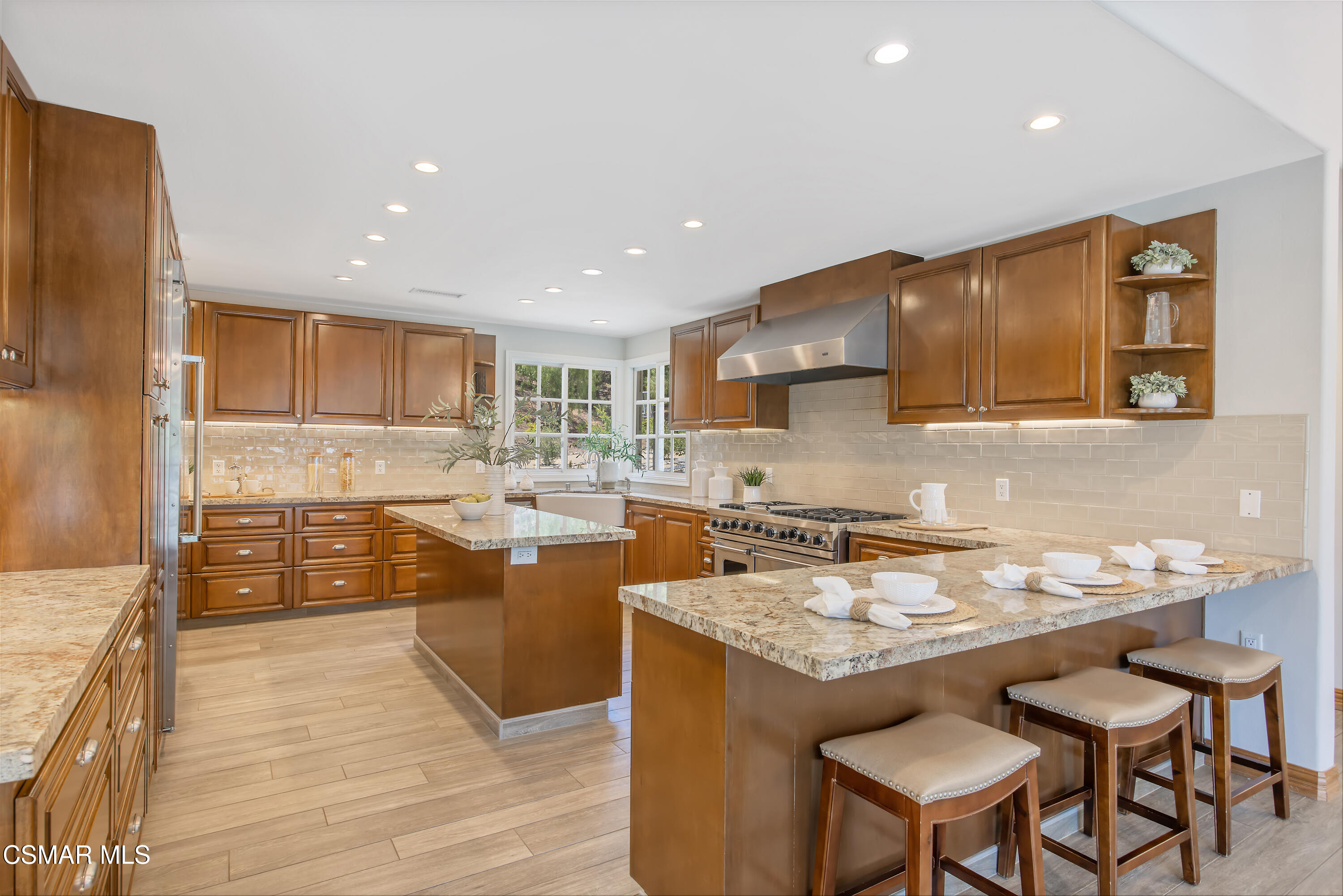 3840 Castle View Road Agoura Hills, CA 91301 - Photo 18 of 94 a kitchen with a stove a sink a kitchen island with chairs and wooden cabinets