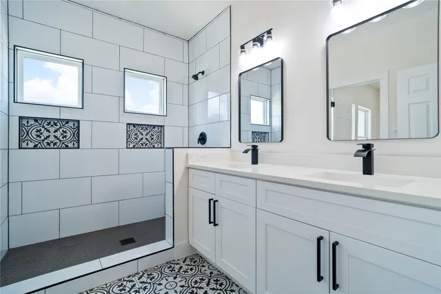 a bathroom with a double vanity sink a mirror and shower