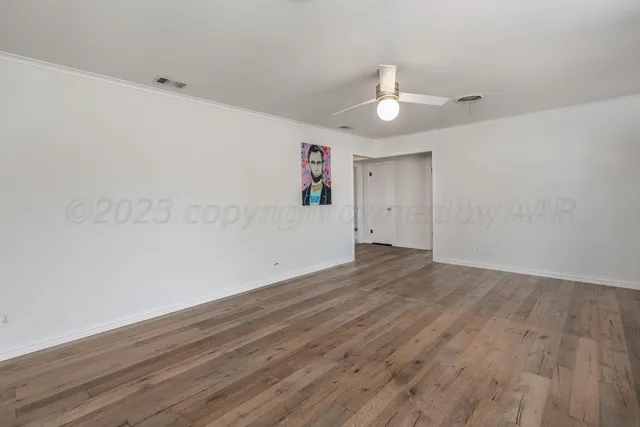 an empty room with wooden floor ceiling fan and window