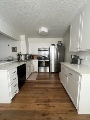 a large kitchen with cabinets wooden floor and stainless steel appliances