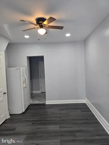 a view of an empty room with wooden floor and a ceiling fan