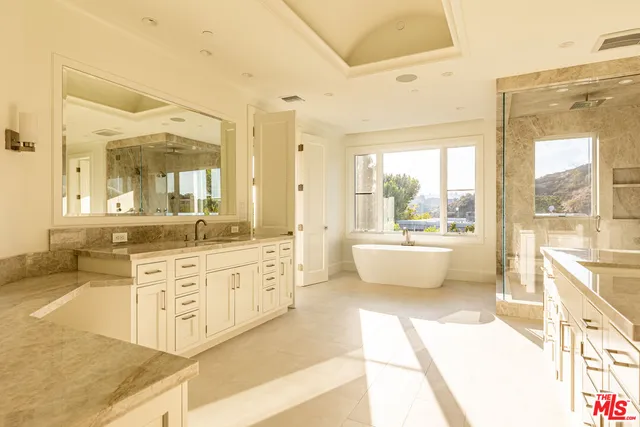 a spacious bathroom with a double vanity sink large mirror and a bathtub