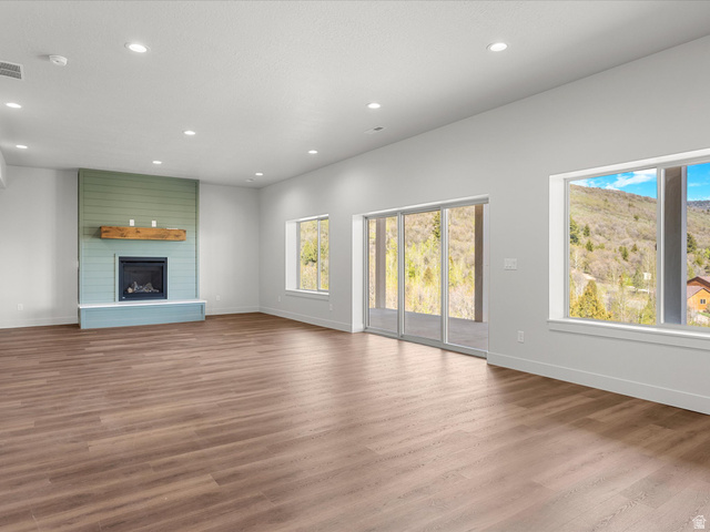 1159 North Broad Hollow Road Garden City, UT 84028 - Photo 8 of 55 Spacious interior featuring wood-finish flooring, a contemporary fireplace with a wood mantle and shiplap accent wall, recessed lighting, and large windows with sliding glass doors
