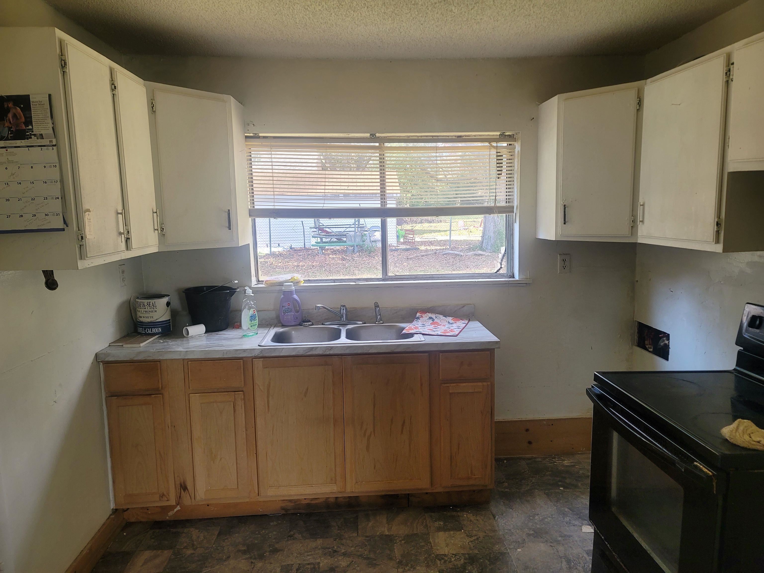 516 East Raines Road Memphis, TN 38109 - Photo 24 of 34 Kitchen with electric range, light countertops, a textured ceiling, stone finish flooring, and white cabinets
