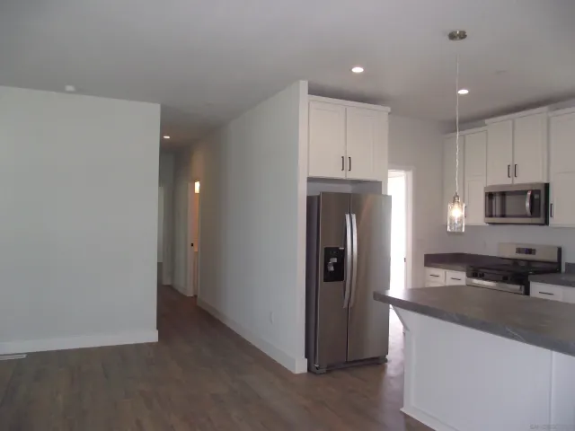 a kitchen with stainless steel appliances granite countertop a refrigerator a stove and a sink