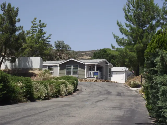 a front view of a house with a garden and trees