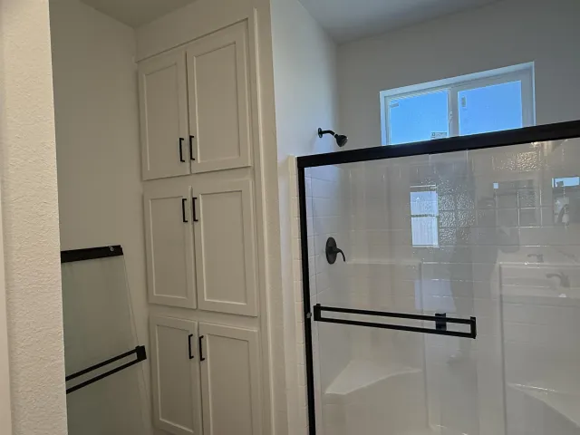 a view of a refrigerator in kitchen and white cabinets