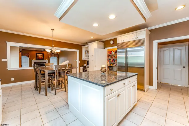 a kitchen with stainless steel appliances kitchen island granite countertop a table chairs and a refrigerator