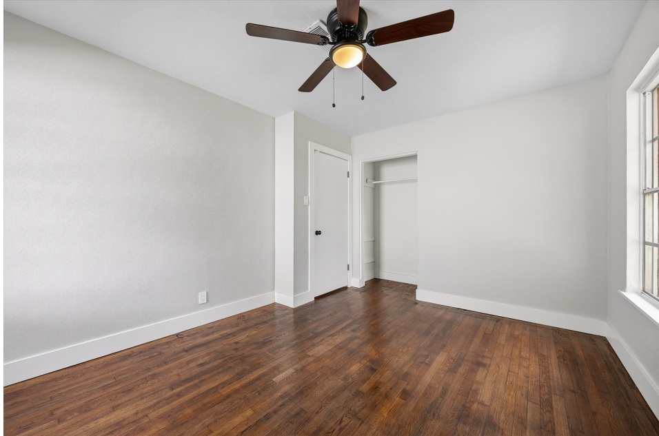 1402 Kent Street Taylor, TX 76574 - Photo 19 of 25 an empty room with wooden floor ceiling fan and window
